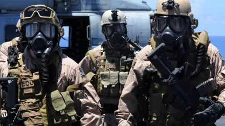 Three soldiers in tactical gear wearing gas masks stand confidently in front of a military helicopter, showcasing a strong military presence in this HD PC desktop wallpaper.