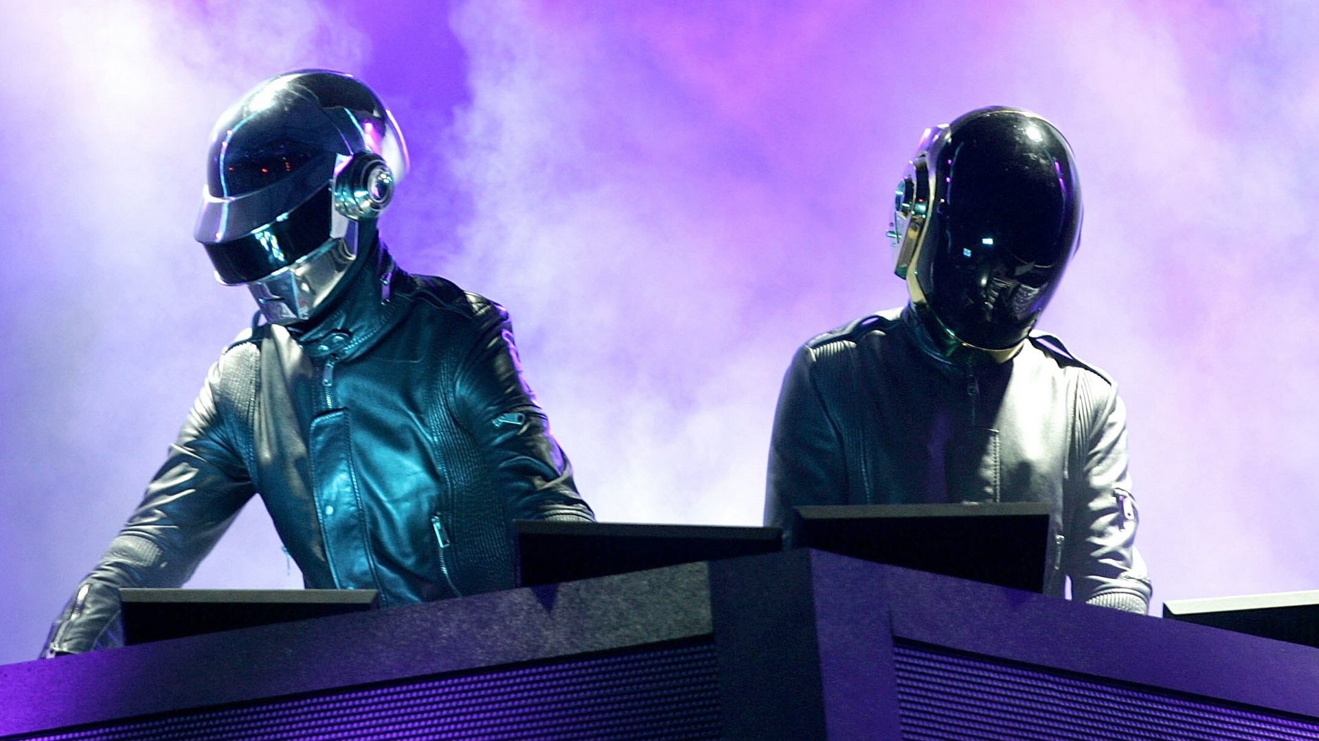 HD PC wallpaper of two helmeted electronic music performers at a DJ console, backlit by purple haze.