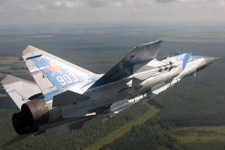 Mikoyan MiG-31 jet fighter in flight over a forested landscape, military aircraft imagery rendered as a 2K Quad HD PC desktop wallpaper and background, tail number 903 visible.