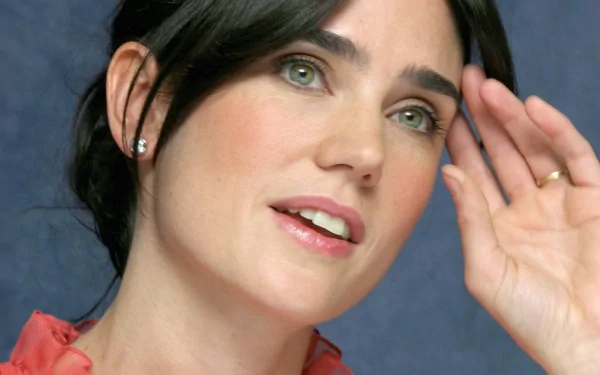 HD desktop wallpaper featuring Jennifer Connelly, showcasing her expressive gaze and elegant style against a soft blue background.