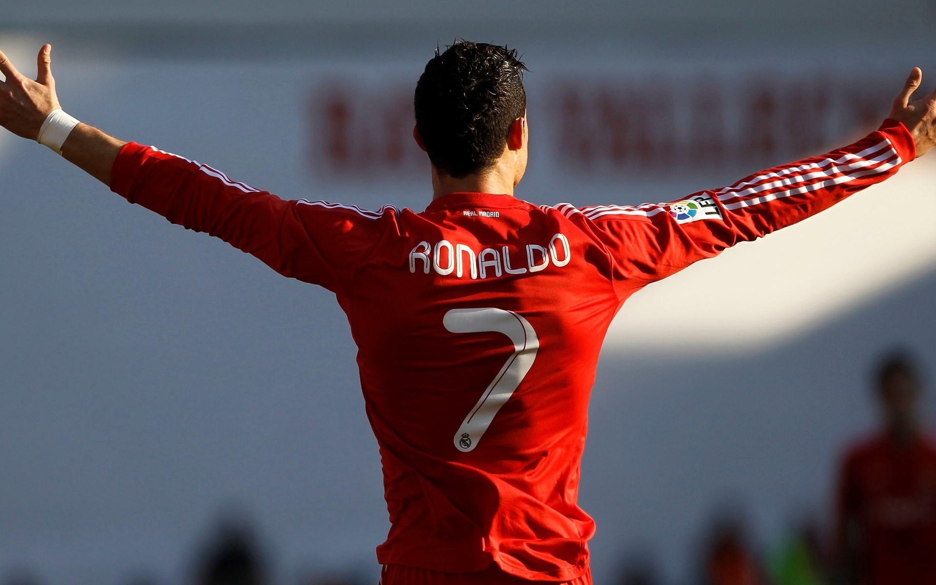 HD wallpaper featuring soccer player Cristiano Ronaldo in a red jersey with arms outstretched, viewed from behind on the field.