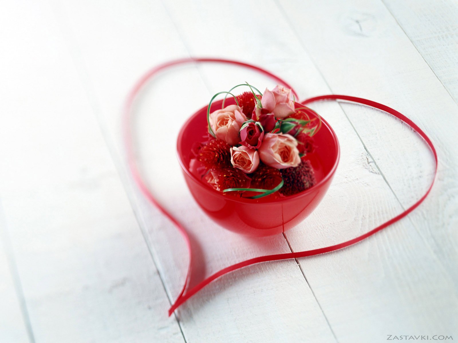 A vibrant red bowl filled with fresh strawberries and delicate pink roses, elegantly arranged with a flowing ribbon in the shape of a heart, capturing the essence of love. HD desktop wallpaper.