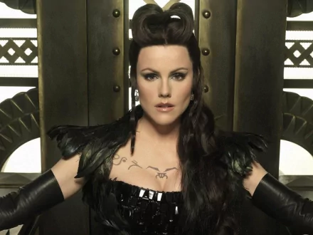 HD PC desktop wallpaper of a dark-haired woman in an ornate black costume from the TV show Tin Man, seated against an art-deco metallic backdrop with a fierce gaze.