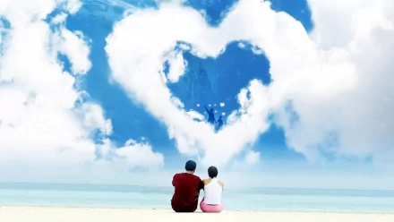 An HD desktop wallpaper showing an artistic scene of a couple sitting on a beach, looking at a large heart-shaped cloud in the sky, evoking feelings of love and serenity.