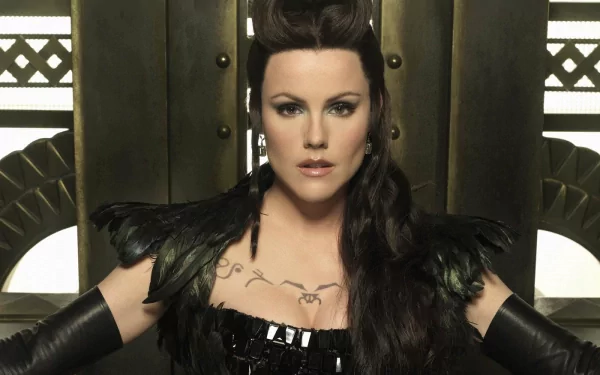 HD PC desktop wallpaper of a dark-haired woman in an ornate black costume from the TV show Tin Man, seated against an art-deco metallic backdrop with a fierce gaze.