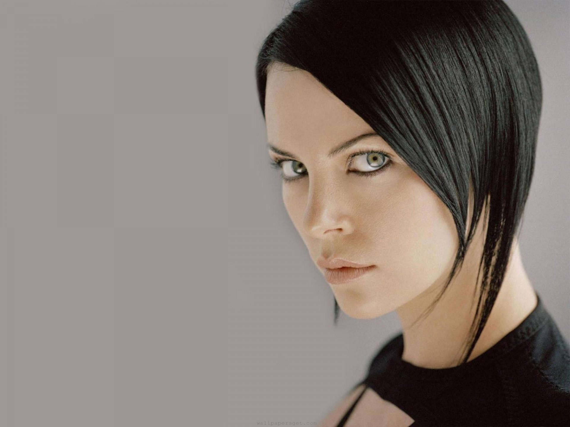 HD desktop wallpaper of Charlize Theron as Aeon Flux from the movie, featuring a close-up portrait with sleek black hair and a serious expression.