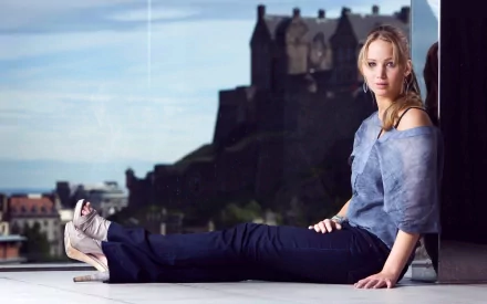 Jennifer Lawrence poses elegantly in this HD desktop wallpaper, featuring a stunning background of a castle and cityscape, showcasing her stylish outfit and confident demeanor.