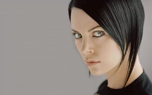 HD desktop wallpaper of Charlize Theron as Aeon Flux from the movie, featuring a close-up portrait with sleek black hair and a serious expression.