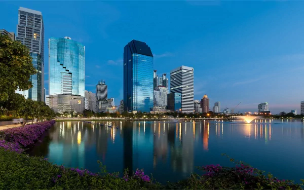 HD desktop wallpaper of Bangkok's city skyline with skyscrapers reflecting on a lake in Thailand during twilight.