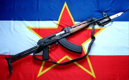 HD PC desktop wallpaper of an AKM assault rifle laid diagonally on a red-white-blue flag with a yellow-outlined red star, man-made military hardware as the background.