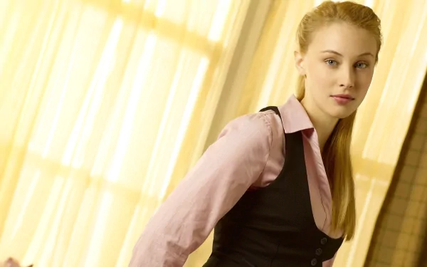 HD PC desktop wallpaper featuring celebrity Sarah Gadon in a soft-lit setting, wearing a light pink shirt with a black vest, against a warm, yellow curtain background.