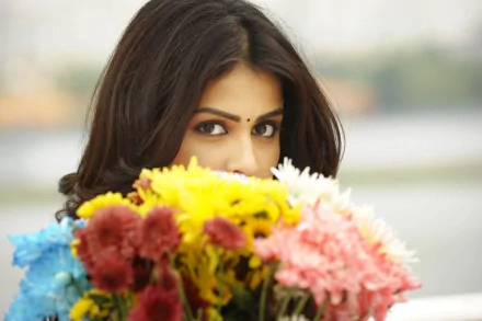 HD desktop wallpaper featuring celebrity Genelia D'souza partially hidden behind a vibrant bouquet of colorful flowers.