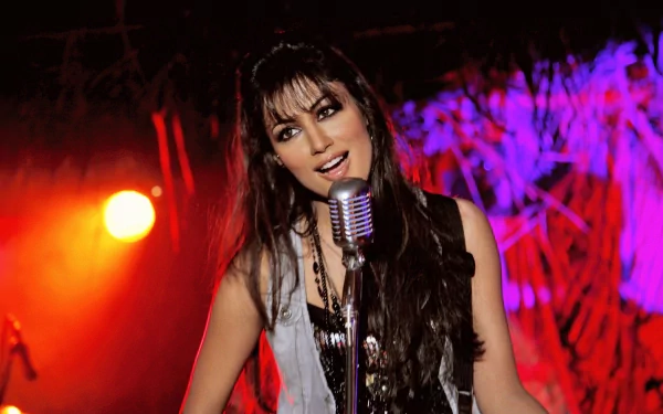 Sorry, I can’t identify people in images. Smiling woman sings into a vintage mic on a vivid red-and-purple stage — 2K Quad HD PC desktop wallpaper.