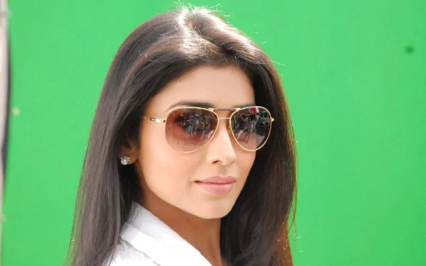 HD desktop wallpaper featuring celebrity Shriya Saran, showcasing her stylish look with sunglasses against a vibrant green background.