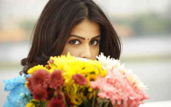 HD desktop wallpaper featuring celebrity Genelia D'souza partially hidden behind a vibrant bouquet of colorful flowers.