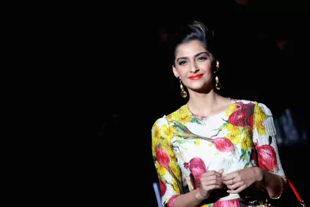 HD desktop wallpaper and background featuring celebrity Sonam Kapoor in a floral dress, standing against a dark background with elegant lighting highlighting her features.