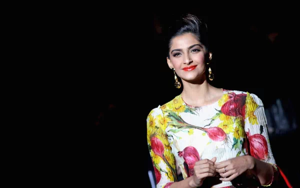 HD desktop wallpaper and background featuring celebrity Sonam Kapoor in a floral dress, standing against a dark background with elegant lighting highlighting her features.