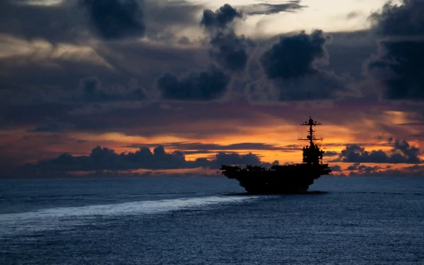 The USS George Washington (CVN-73) aircraft carrier sails at dusk, silhouetted against a dramatic sky over the ocean in this HD military warship wallpaper.