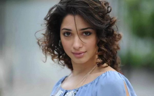 HD PC desktop wallpaper: close-up portrait of a celebrity actress with curly hair in a blue off-shoulder top, soft blurred background.