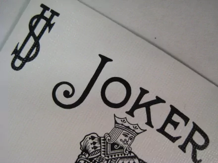 A close-up view of a Joker playing card, featuring intricate designs and the iconic dollar sign, making it a striking HD desktop wallpaper and background.