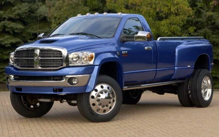 HD PC desktop wallpaper of a blue Dodge vehicle — a heavy-duty dually pickup truck parked on a paved area with trees in the background.
