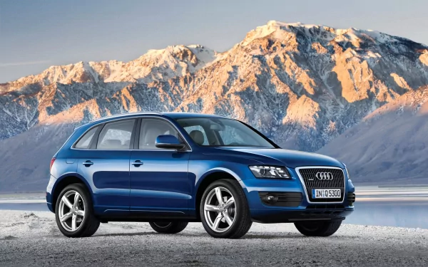 Blue Audi Q5 vehicle on a frozen shore with snow-capped mountains at sunrise — HD PC desktop wallpaper and background.