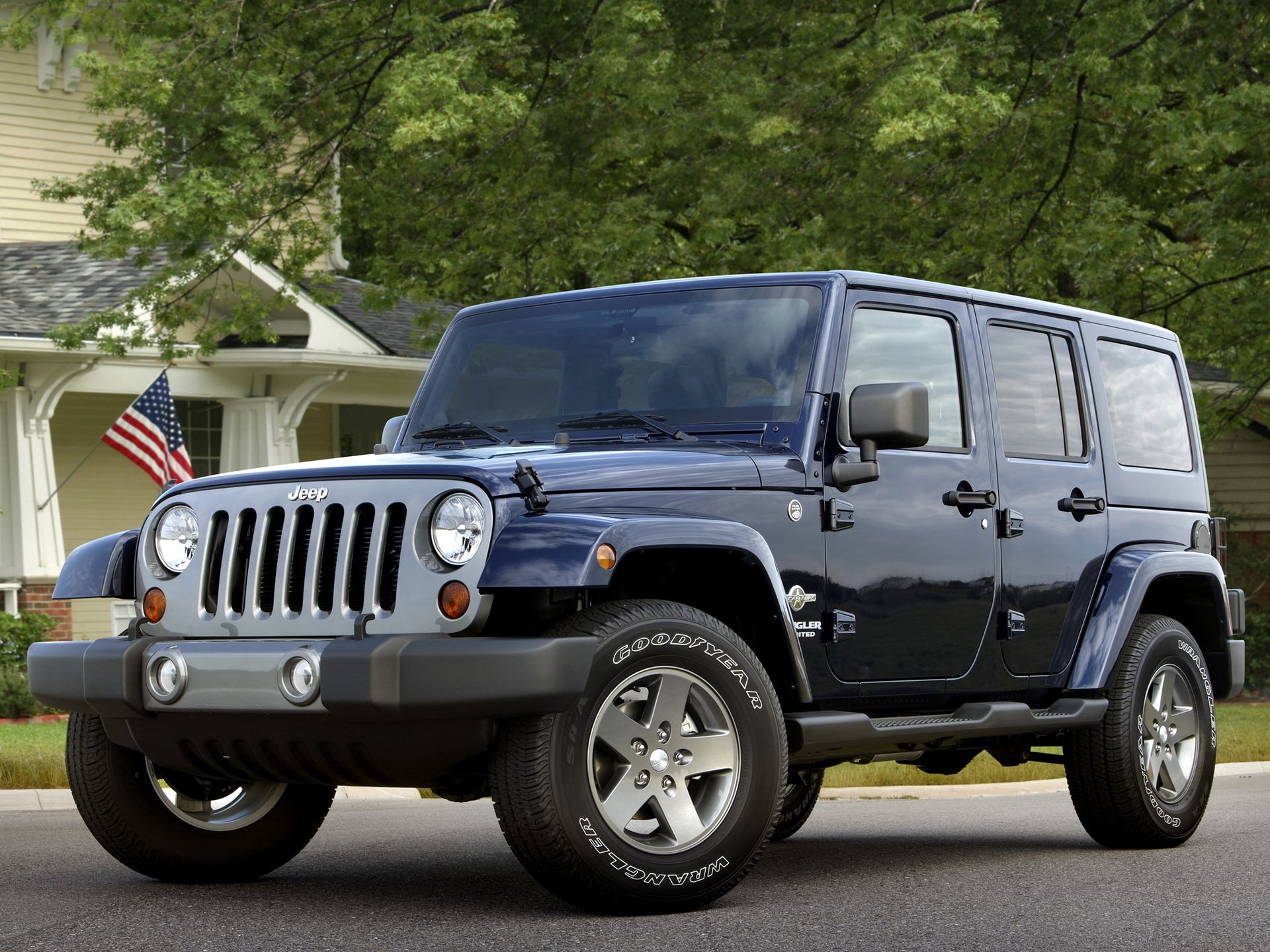 A vibrant blue Jeep parked on a suburban street, framed by a house and an American flag. This HD image makes an engaging desktop wallpaper and background.
