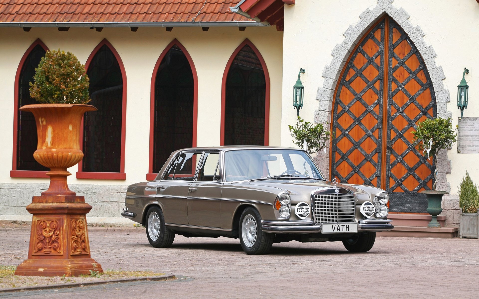 HD PC desktop wallpaper featuring a classic Mercedes vehicle parked in front of a building with arched windows and an ornate wooden door.