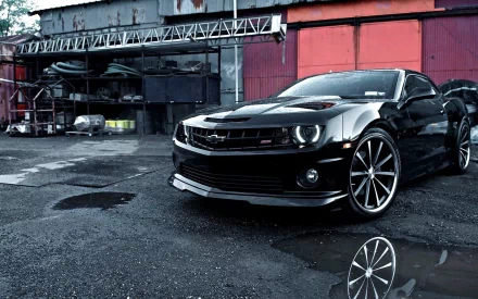 HD desktop wallpaper featuring a black Chevrolet Camaro SS parked in an industrial setting, showcasing the sleek design of this powerful Chevrolet car.