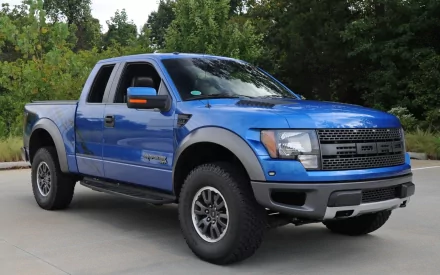 HD PC desktop wallpaper featuring a blue Ford Raptor truck parked outdoors with trees in the background.