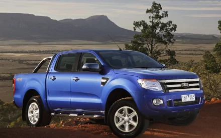 HD PC desktop wallpaper featuring a blue Ford Ranger parked on a dirt path with mountains and trees in the background.