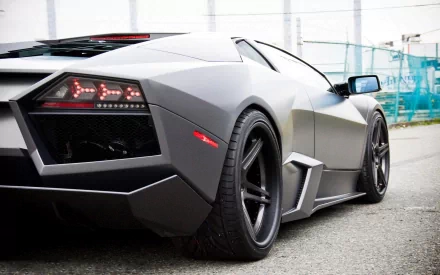 HD PC desktop wallpaper showcasing the sleek rear view of a matte grey Lamborghini Reventon parked on an urban street.