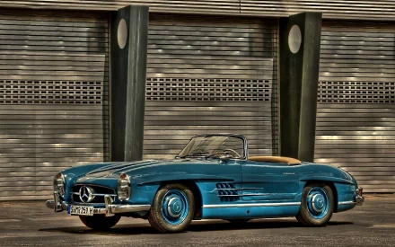 HD desktop wallpaper featuring a blue Mercedes-Benz 300SL convertible parked in front of an industrial shutter backdrop.