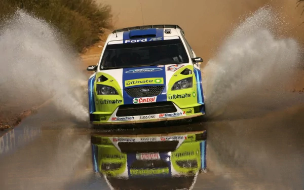 HD PC desktop wallpaper/background featuring a Ford Focus rally car splashing through water, frontal view with vivid yellow-green livery and mirrored reflection on the wet surface.
