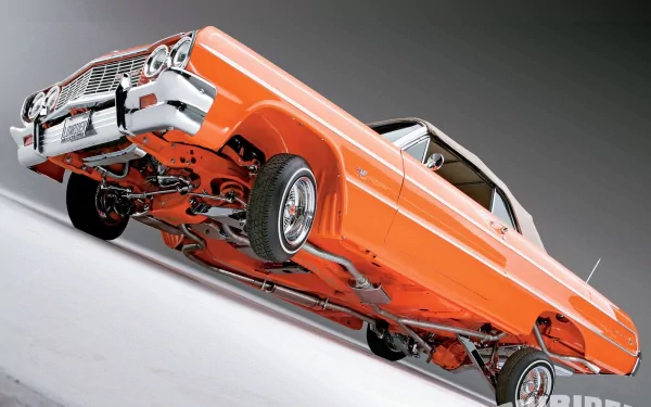 HD PC desktop wallpaper: orange Chevrolet lowrider with raised chrome suspension and custom wheels, shown from a dramatic low angle.