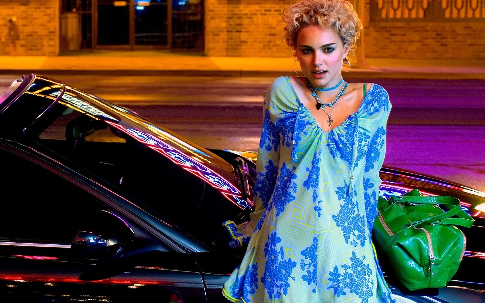 A vibrant HD desktop wallpaper featuring Natalie Portman, showcasing her stylish look against a backdrop of neon lights and a sleek black car.