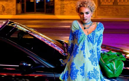 A vibrant HD desktop wallpaper featuring Natalie Portman, showcasing her stylish look against a backdrop of neon lights and a sleek black car.