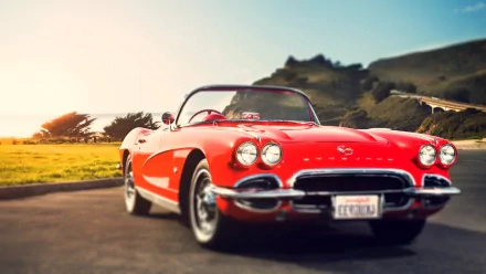 HD PC desktop wallpaper featuring a classic red Chevrolet convertible parked on a scenic road with mountains and a bright sky in the background.