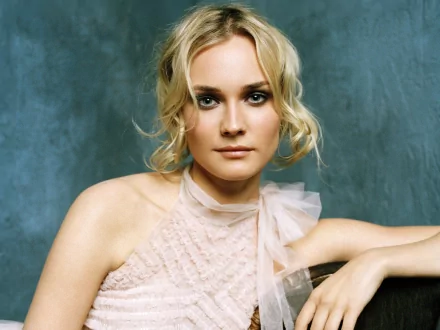 HD PC desktop wallpaper featuring celebrity Diane Kruger with a soft expression, styled in a delicate, light-colored outfit against a textured blue-gray background.