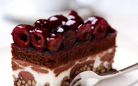 A close-up of a chocolate dessert topped with cherry glaze and cherries, presented on a plate with a fork, makes an enticing HD desktop wallpaper and background.