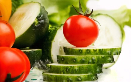 HD PC desktop wallpaper featuring fresh sliced cucumbers and vibrant red cherry tomatoes with green leafy background, highlighting healthy food and vegetables.