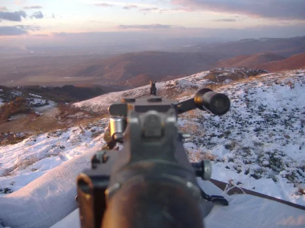 2K Quad HD PC desktop wallpaper: close-up of a man-made rifle's iron sights aimed across a snow-dusted hillside at dusk.