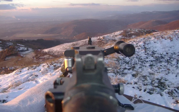 2K Quad HD PC desktop wallpaper: close-up of a man-made rifle's iron sights aimed across a snow-dusted hillside at dusk.