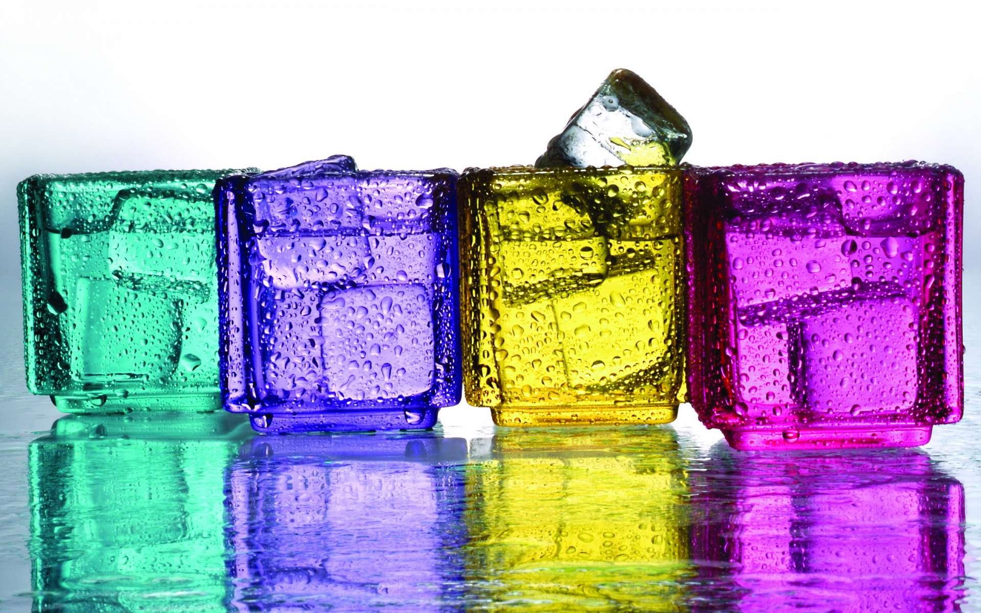 Artistic CGI HD PC desktop wallpaper of four translucent colored glass cubes—teal, blue, yellow, magenta—with bubbles, one tilted, reflected on a glossy surface.