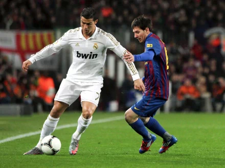 Real Madrid's Cristiano Ronaldo and Barcelona's Lionel Messi vie for the ball during a soccer match. The HD wallpaper captures the intensity of the iconic sports rivalry.