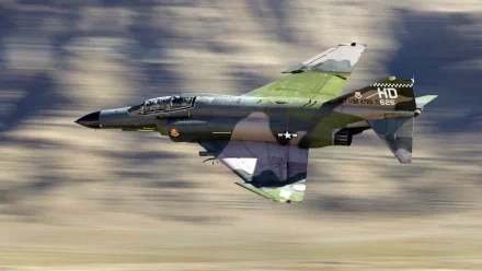 A McDonnell Douglas F-4 Phantom II jet in flight, showcasing its military design and vibrant camouflage, captured in an HD desktop wallpaper format.