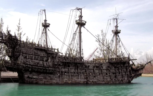 A detailed HD wallpaper showcasing a weathered pirate ship from Pirates of the Caribbean, set against a tranquil water backdrop.
