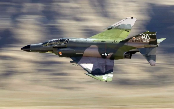 A McDonnell Douglas F-4 Phantom II jet in flight, showcasing its military design and vibrant camouflage, captured in an HD desktop wallpaper format.