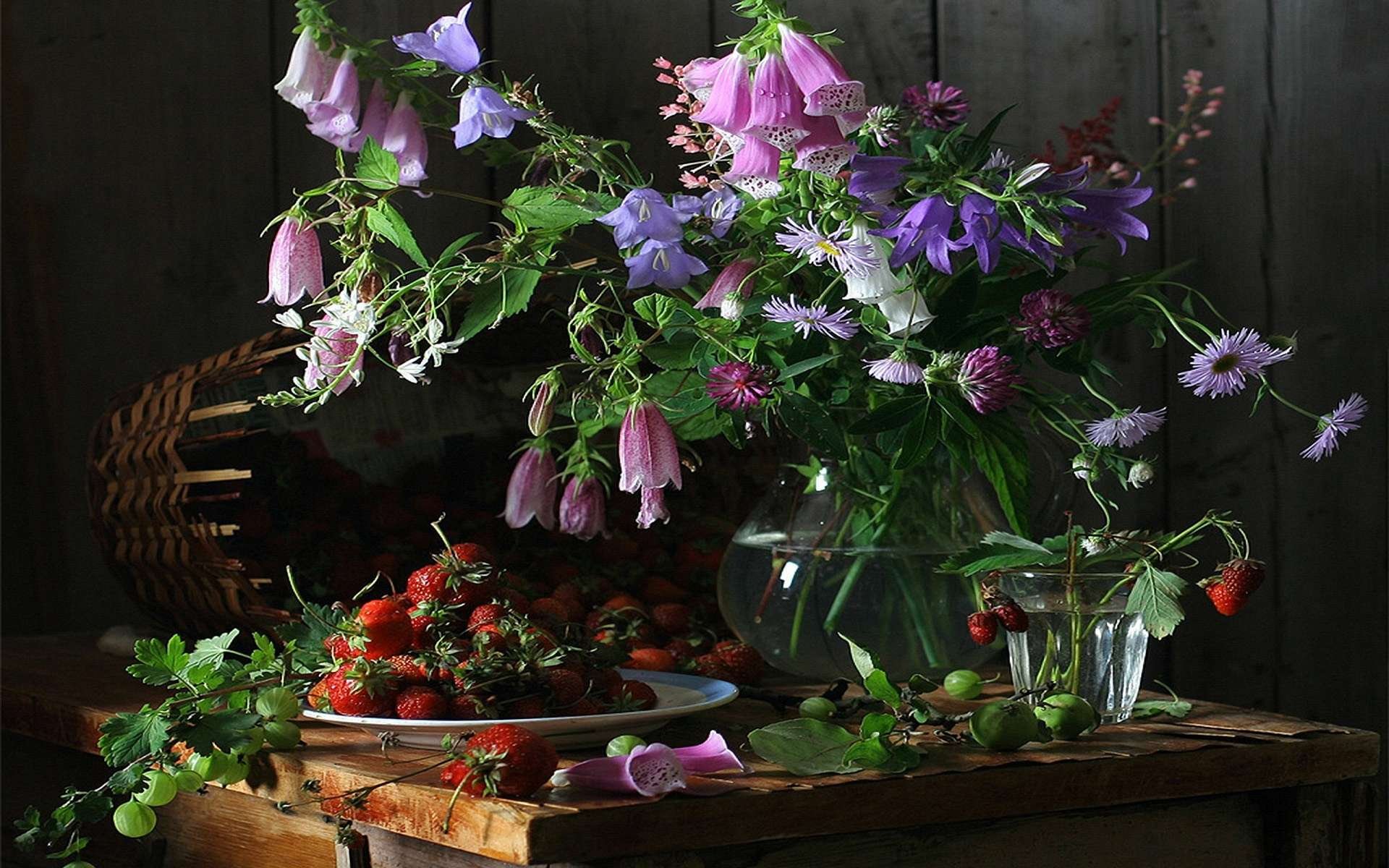 HD desktop wallpaper featuring a rustic still life with fresh strawberries on a plate, accompanied by wildflowers in glass vases on a wooden table.