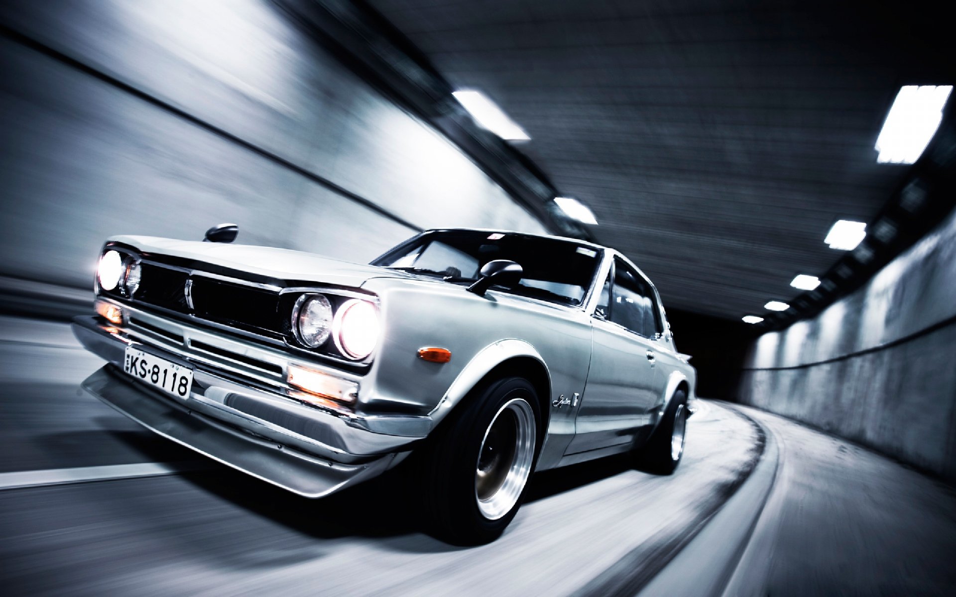 HD desktop wallpaper featuring a silver Nissan Skyline GT-R speeding through a tunnel, highlighting its classic design and dynamic motion.
